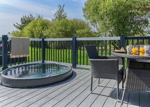 A hot tub on a wooden deck with wicker chairs and a table set for breakfast. - Luxury 2 bed HT (Pet) (Hayle)