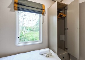 A bedroom with a window, a bed with a white towel, and a wardrobe. - Luxury 2 bedroom Hot Tub sleeps 6 (Pet Friendly) (Hayle)