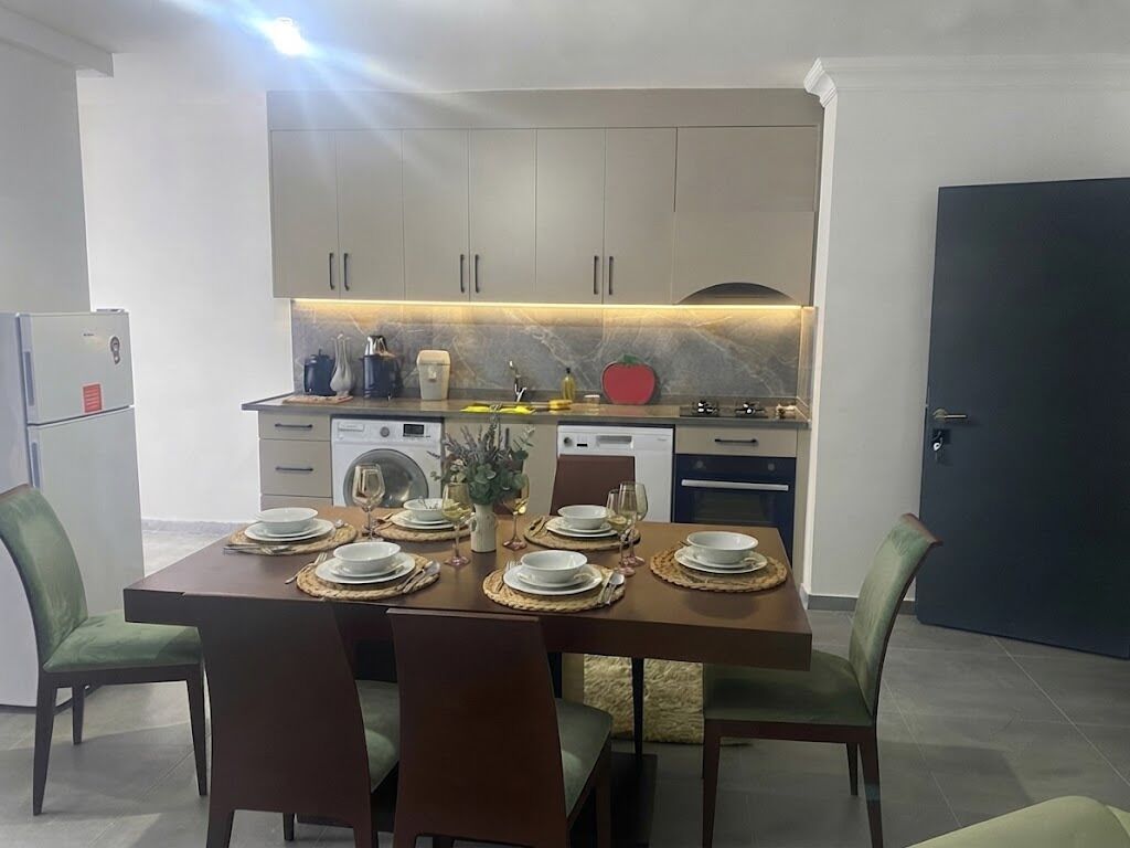 Une cuisine moderne avec une table à manger pour quatre personnes, équipée d’un réfrigérateur, d’une cuisinière et d’un lave-vaisselle.