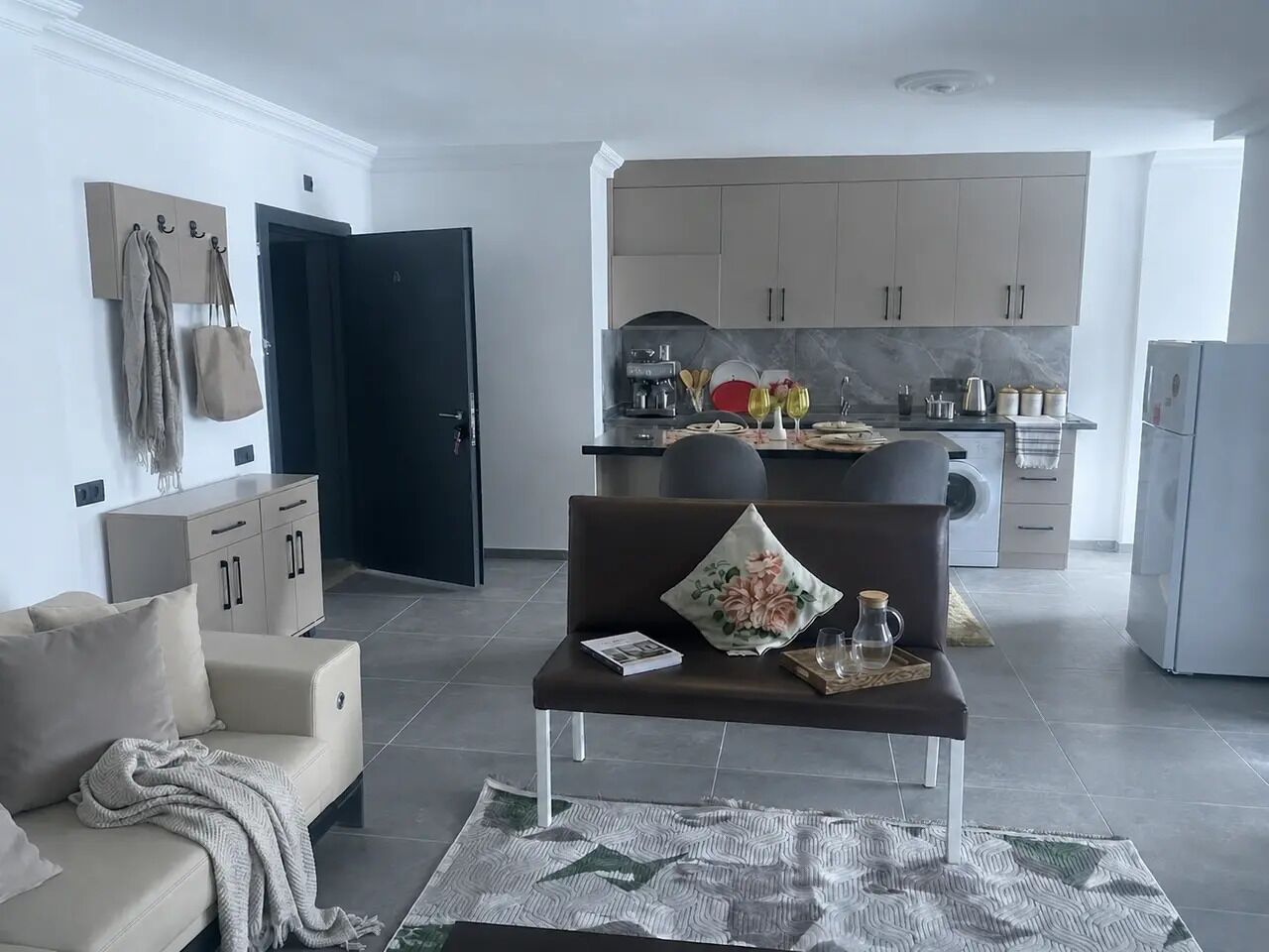 A modern living room with a sofa, a coffee table, and a dining area with a kitchen in the background.