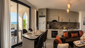 Een moderne keuken met een marmeren aanrecht, een eethoek met een tafel en stoelen, en een bank met kussens.