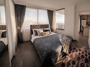 Une chambre d’hôtel moderne dotée d’un grand lit, d’une vue sur la mer et d’une kitchenette.