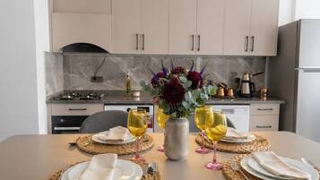 Una mesa de comedor dispuesta con platos, cubiertos y copas de vino, con un jarrón de flores en el centro.