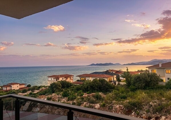 A coastal residential area with houses, a clear sky, and the sea in the background.