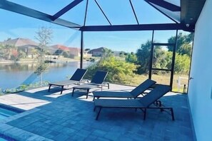 Ein überdachter Außenbereich mit Liegestühlen und einem Pool.