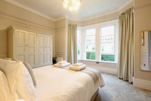 Ein Schlafzimmer mit einem großen Bett, einem Kleiderschrank und einem Fenster mit Vorhängen.
