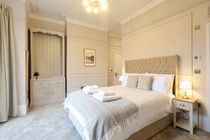 Une chambre d’hôtel avec un grand lit, une table de chevet avec une lampe, une armoire et un tableau encadré au mur.