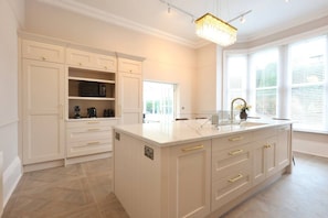 A kitchen with a marble countertop, white cabinetry, and a chandelier. - Somerley Halifax - Luxury 6 Bedroom Stay (West Yorkshire)