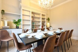 A dining area with a long table set for six, surrounded by brown upholstered chairs. - Somerley Halifax - Luxury 6 Bedroom Stay (West Yorkshire)
