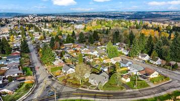 An aerial view of a residential area with houses, roads, and a distant cityscape.