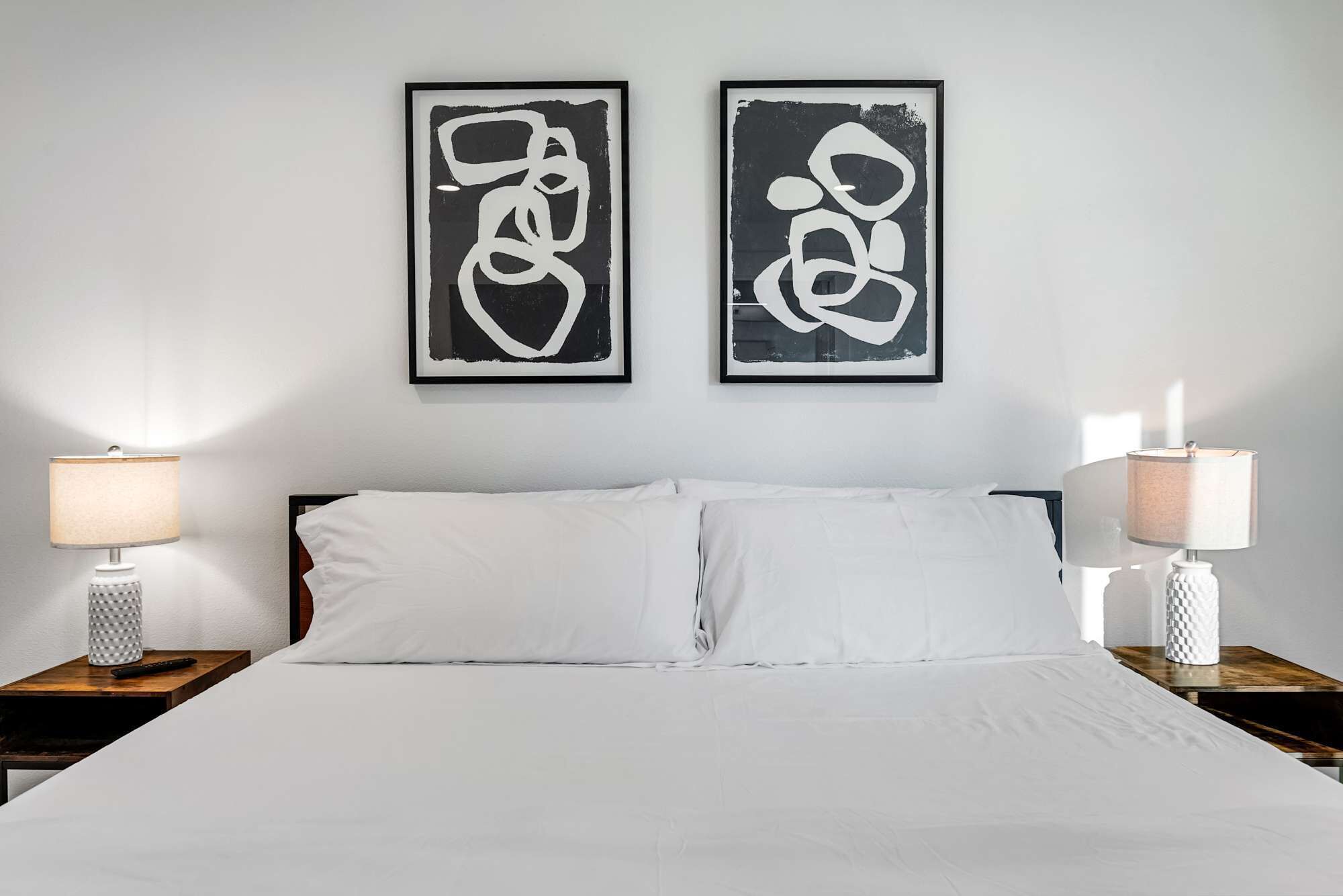 Una camera d'hotel con un letto grande, due comodini e due opere d'arte astratte appese alle pareti.