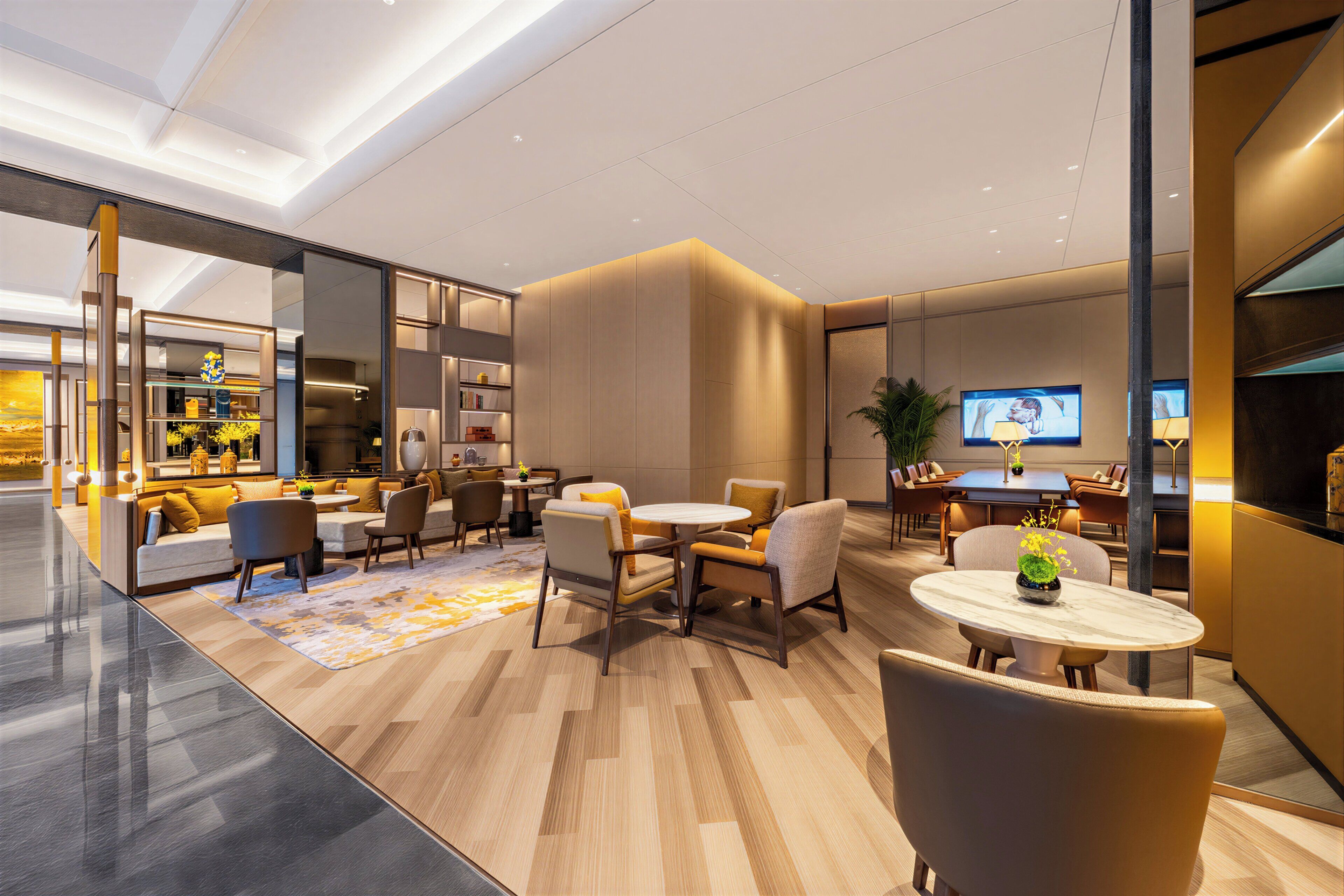 Un hall d’hôtel moderne avec un espace salon, un téléviseur et un comptoir d’accueil.