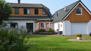 Ein zweistöckiges Haus mit geneigtem Dach, einer Garage und einem gepflegten Rasen mit Blumen.