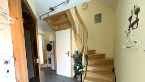 Eine Treppe führt zu einer oberen Etage, im Hintergrund steht eine Waschmaschine und in der Nähe der Treppe ein Blumentopf.