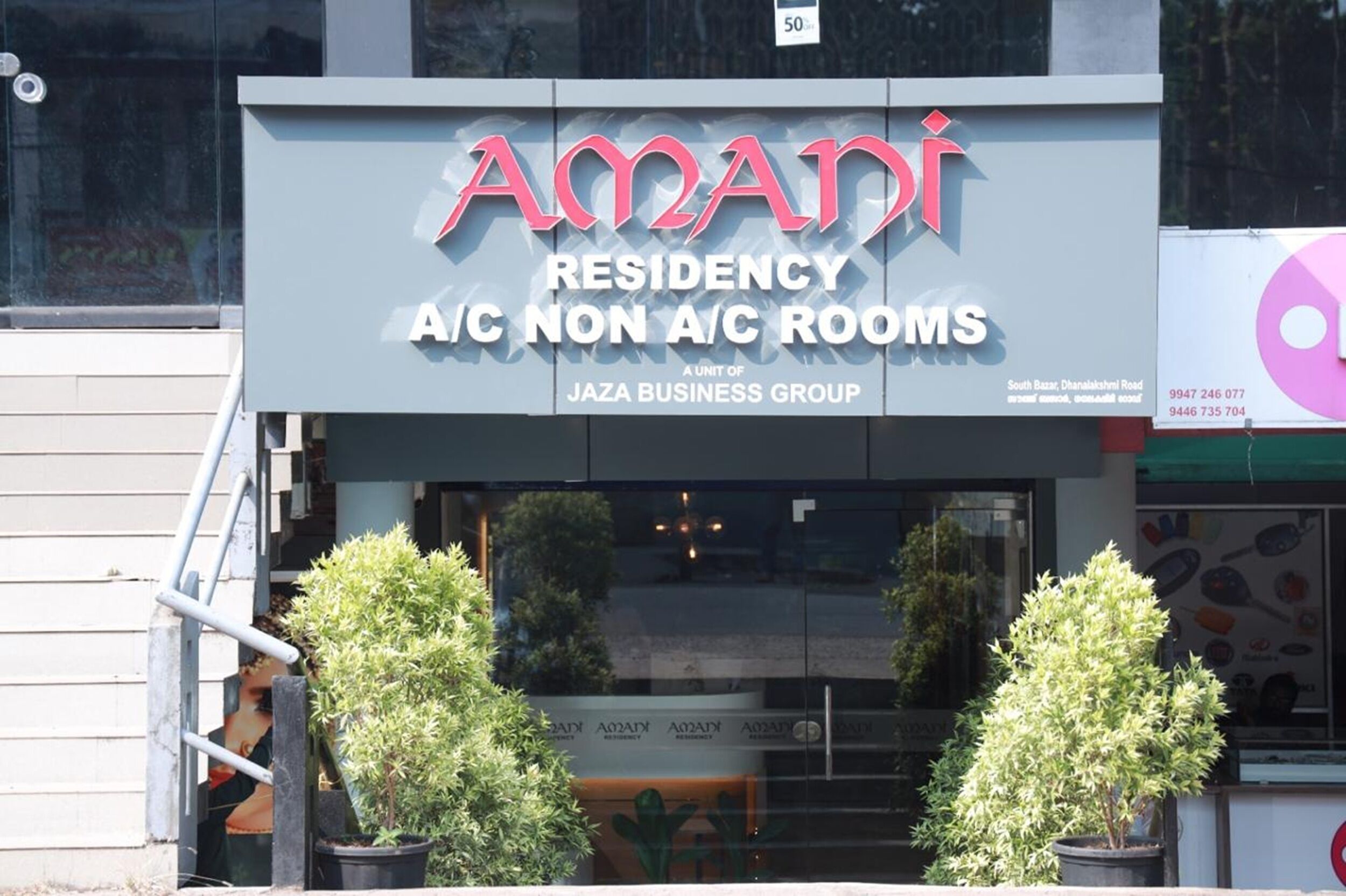 Un edificio con el letrero "Amadi Residency A/C Non A/C Rooms" y "Jaza Business Group".