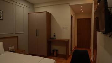 A hotel room with a bed, a wardrobe, a desk, a chair, and a television.