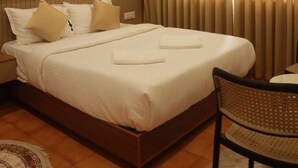 Ein Hotelzimmer mit einem Bett, einem Deckenventilator, einer Klimaanlage, einem gerahmten Bild an der Wand und einem Fenster mit Vorhängen.