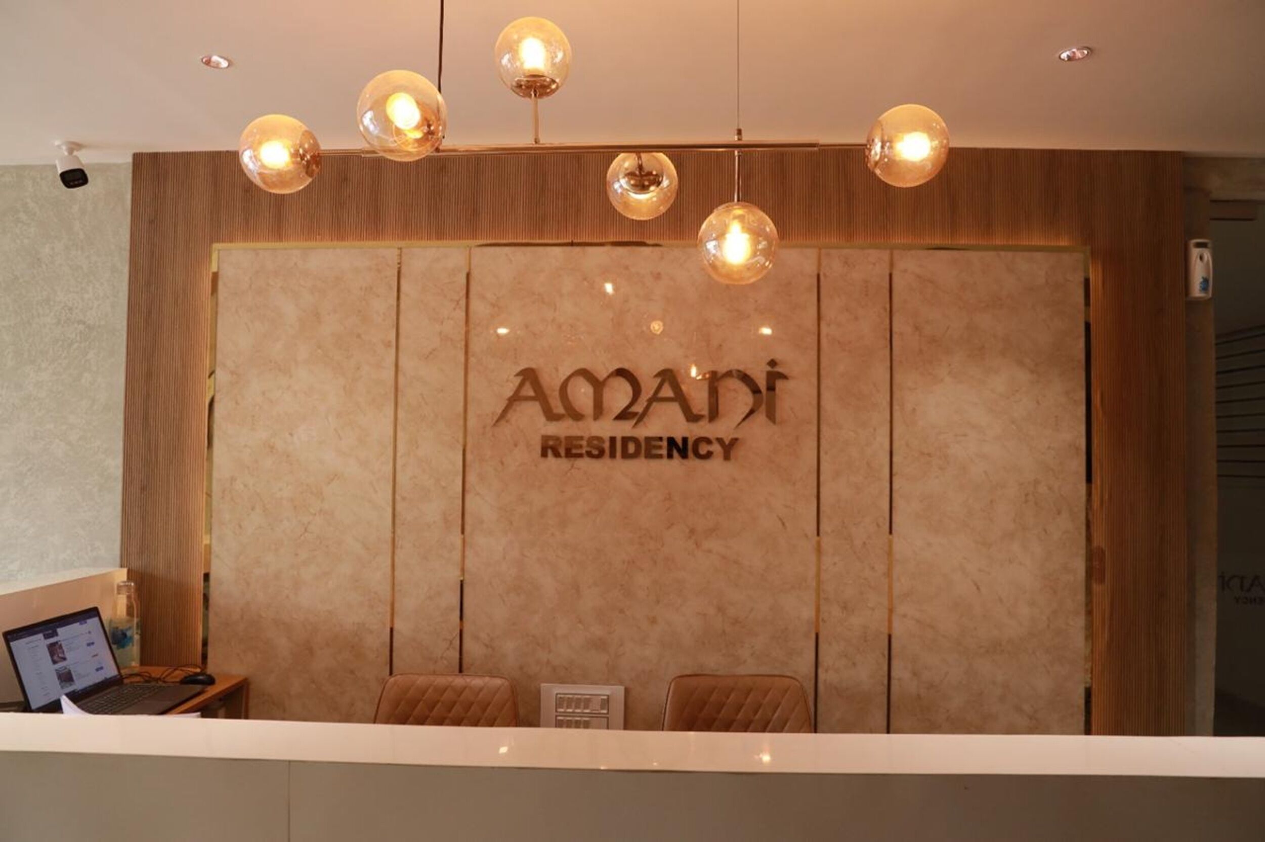 A reception desk with a marble wall and the name "Amari Residency" in the center.