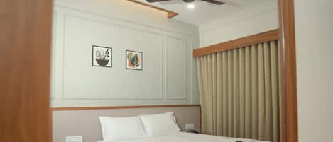 Quarto de hotel bem arrumado com cama, mesa de cabeceira e ventoinha no teto.