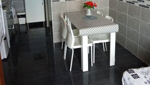 A compact kitchen with a dining area, featuring a refrigerator, a sink, and a tiled backsplash. - Cosy Santa 4 PERS (Le Barcarès)