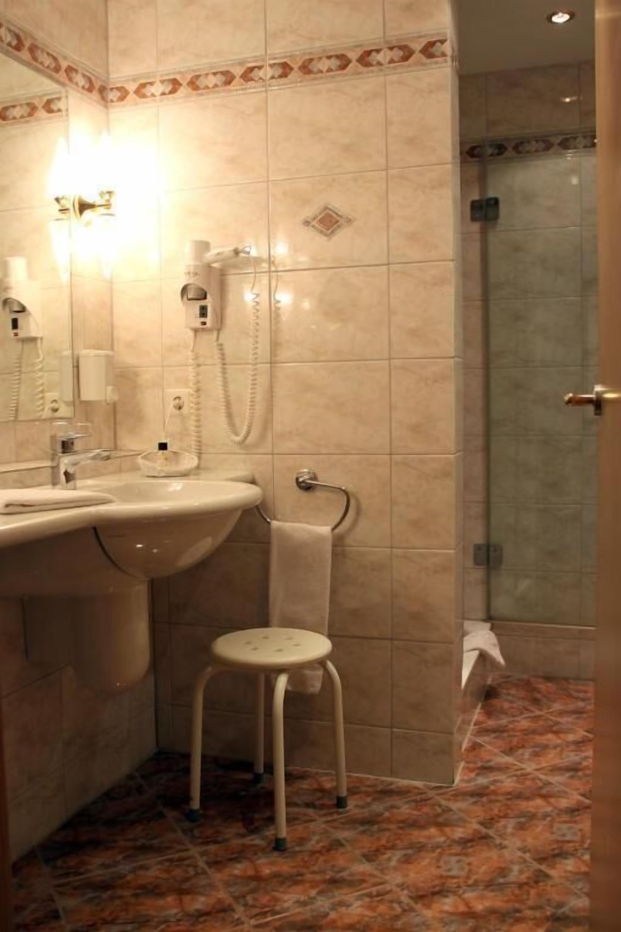 Een badkamer met een wastafel, spiegel, handdoekhouder en douchegedeelte.