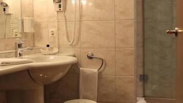 Een badkamer met een wastafel, spiegel, handdoekhouder en douchegedeelte.