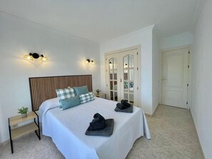 A bedroom with a bed, two bedside tables, a nightstand, a mirror, and a wardrobe with a glass door. - TERRASOL ESTRELLA DE MAR (Torre del Mar)