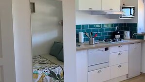 A compact kitchen with white cabinets, a microwave, and a tiled backsplash.