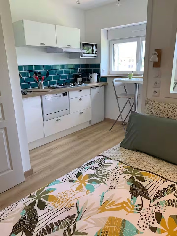 A compact kitchen with white cabinets, a microwave, and a window.