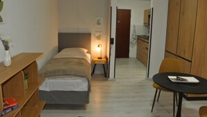 Un dormitorio con cama, mesita de noche, lámpara y un pequeño escritorio con silla.