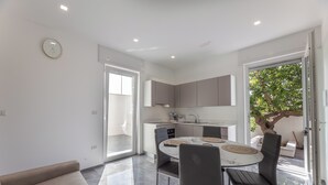 A modern kitchen with a dining area, a sofa, and a view of the outdoors.