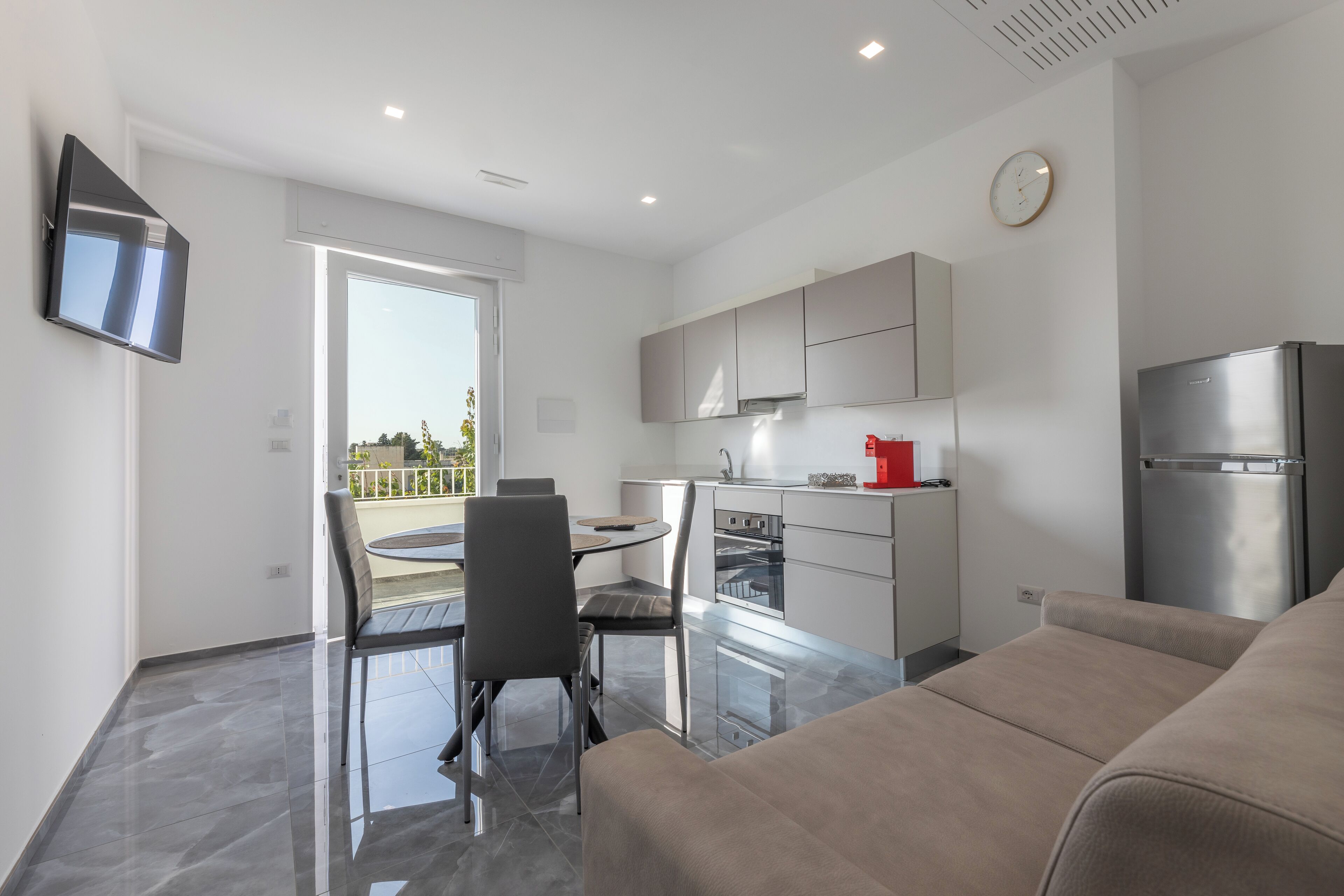 Une cuisine moderne avec un coin repas, un téléviseur à écran plat et un balcon.