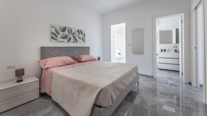 A modern bedroom with a bed, bedside table, and a large mirror.