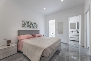 A modern bedroom with a bed, bedside table, and a large mirror. - Sole Apartment (Torre San Giovanni)