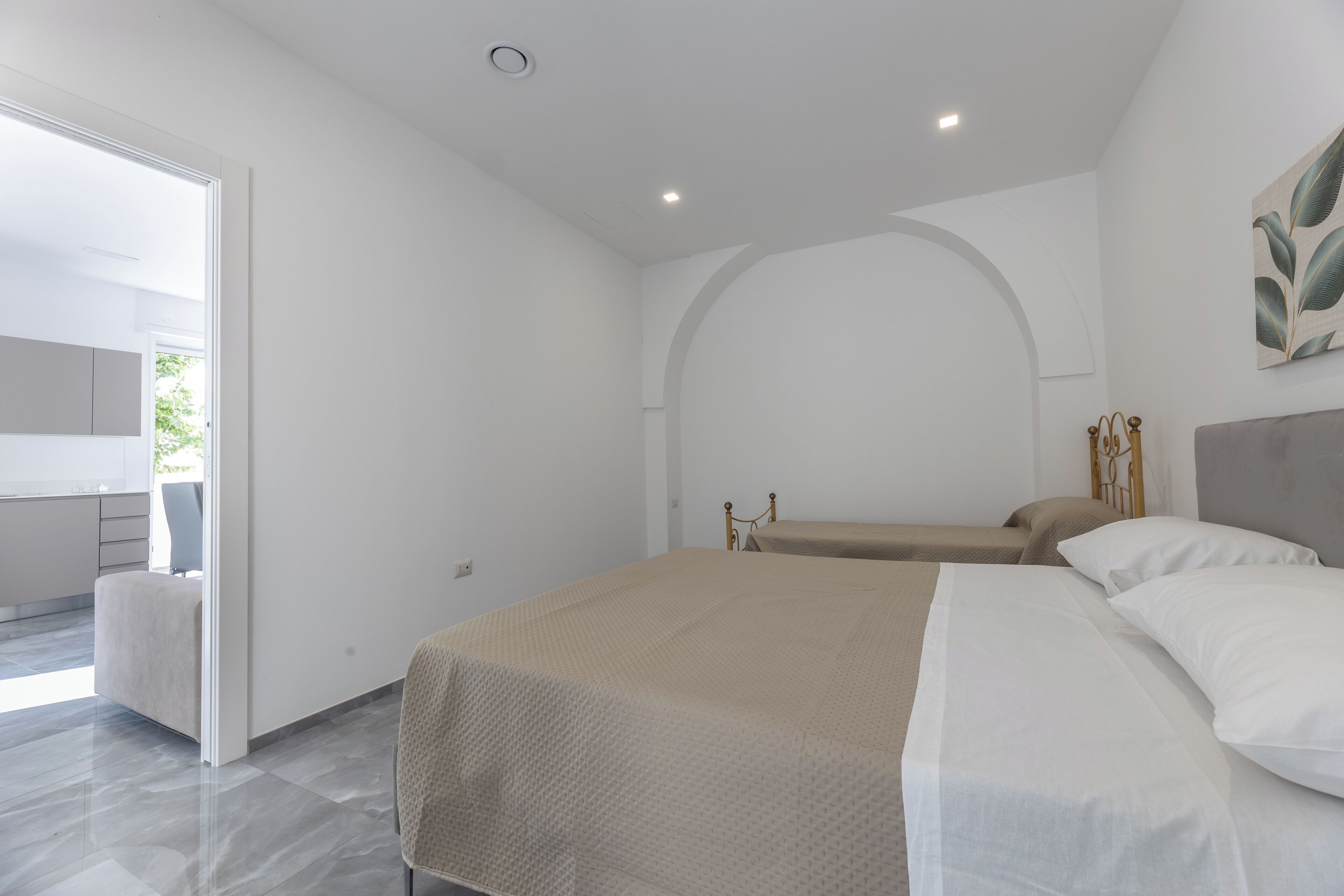 Une chambre à coucher moderne avec un grand lit, un banc et une vue sur l’extérieur.