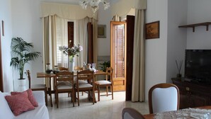 A living room with a dining area, a TV, and a large window with curtains. - From Grandfather Aurelius (Campania)