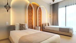 Habitació d'hotel moderna amb un llit gran, un sofà, panells decoratius a la paret i un finestral amb cortines.