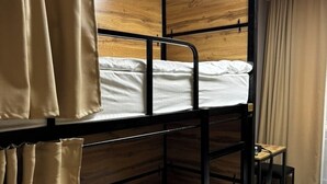 A bunk bed with a wooden headboard, a small table, and beige curtains. - Halo.Hostel (Bishkek)