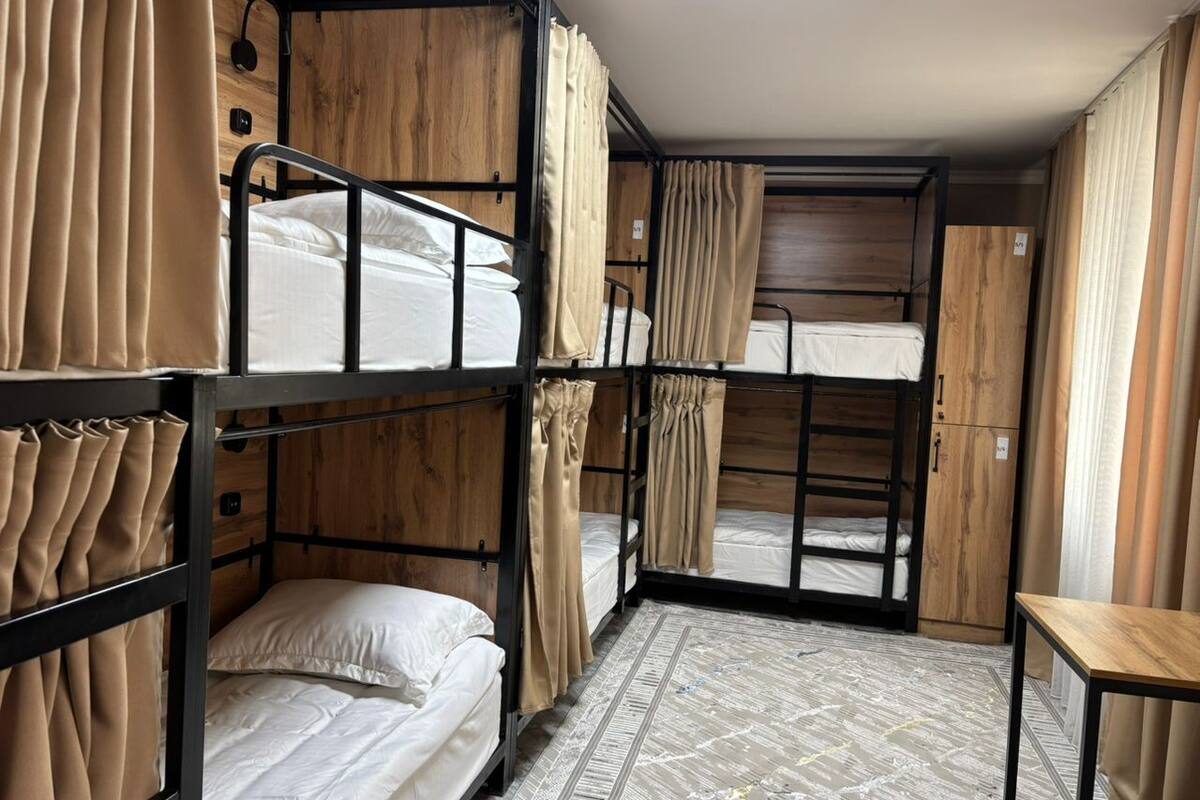 Un dormitorio con literas, paredes de madera, un tragaluz y cortinas.