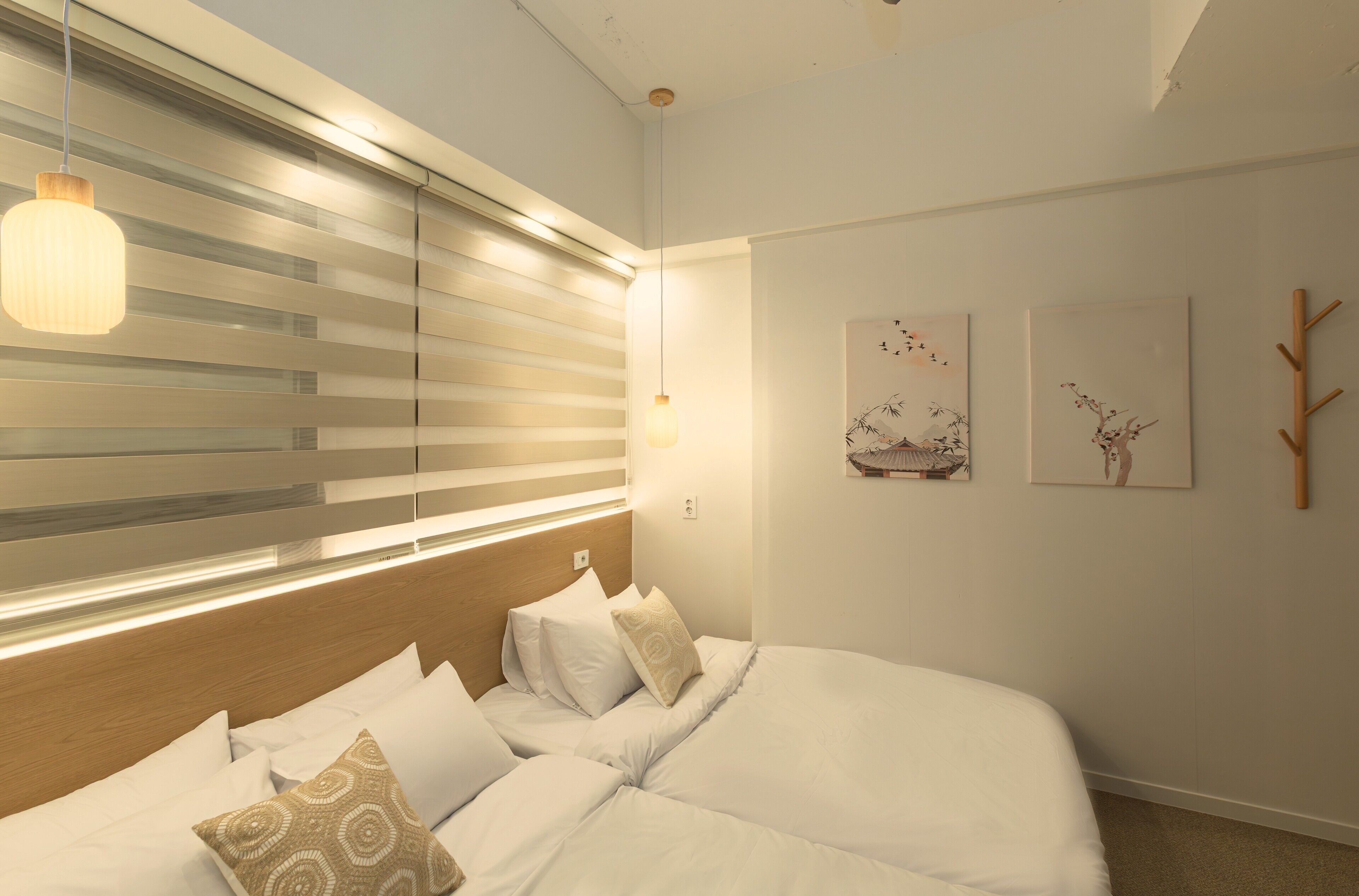 A modern bedroom with a large bed, bedside lamps, and artwork on the wall.