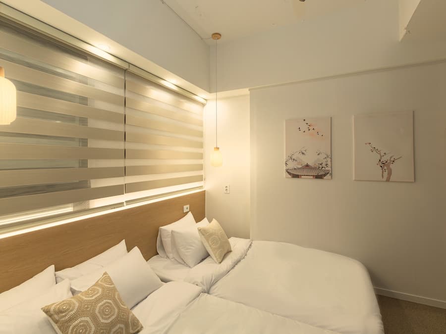 A modern bedroom with a large bed, bedside lamps, and artwork on the wall.