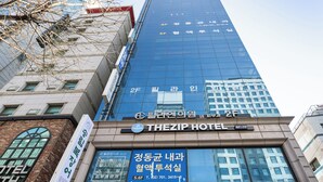 Un hotel con fachada de vidrio moderna, señalización que dice 'THEZIP HOTEL' y el número de la calle a la vista.