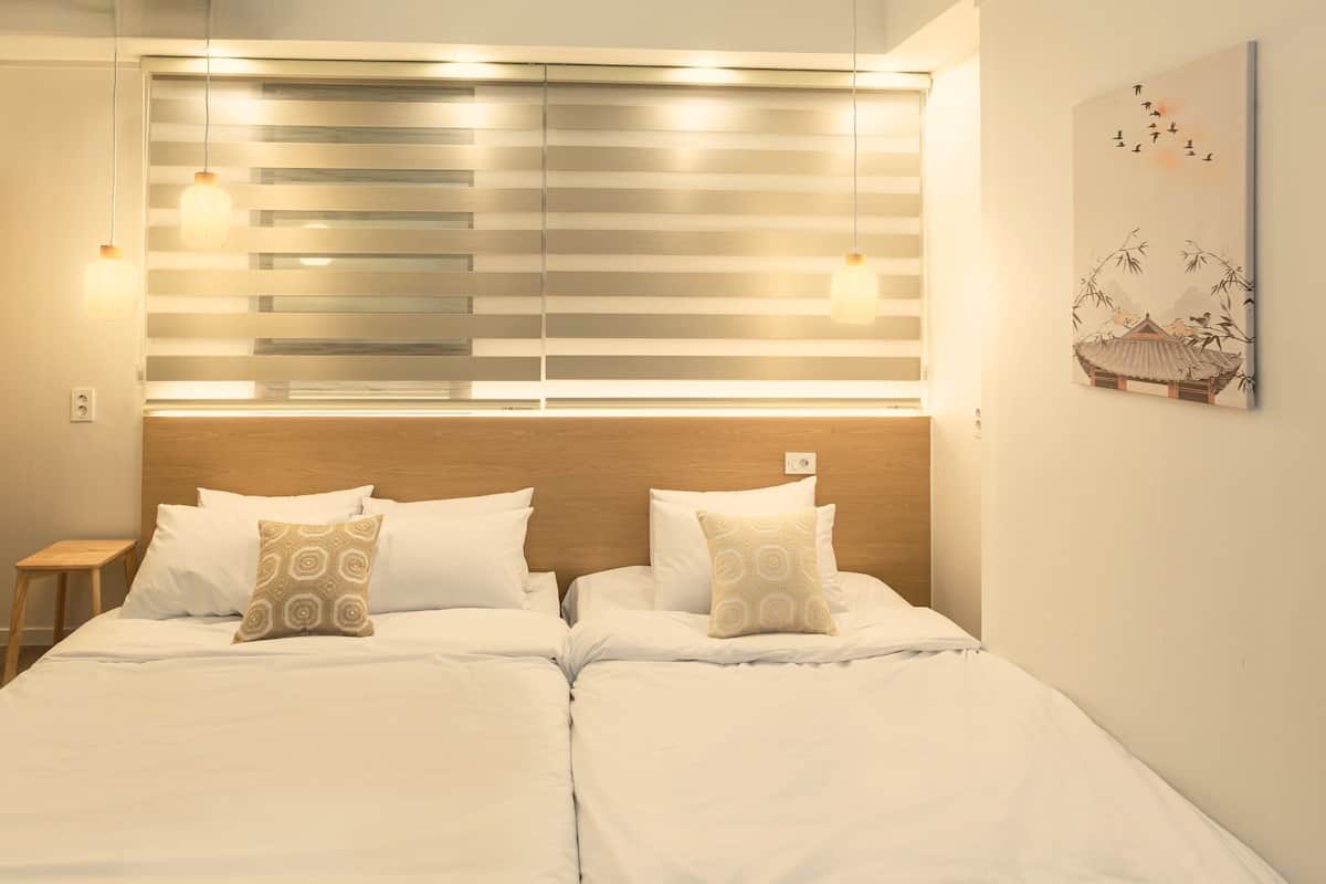 A hotel room with a bed, bedside tables, a wooden headboard, and a wall-mounted artwork.