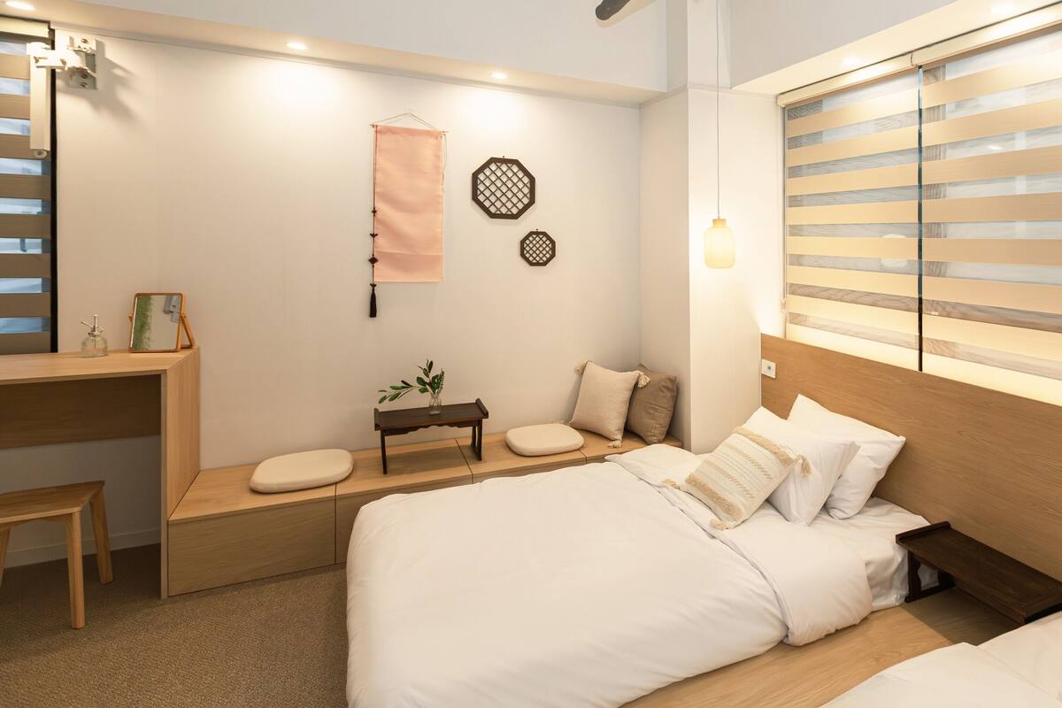 A modern bedroom with a wooden headboard, a bedside table, a bench, and a wall-mounted shelf.