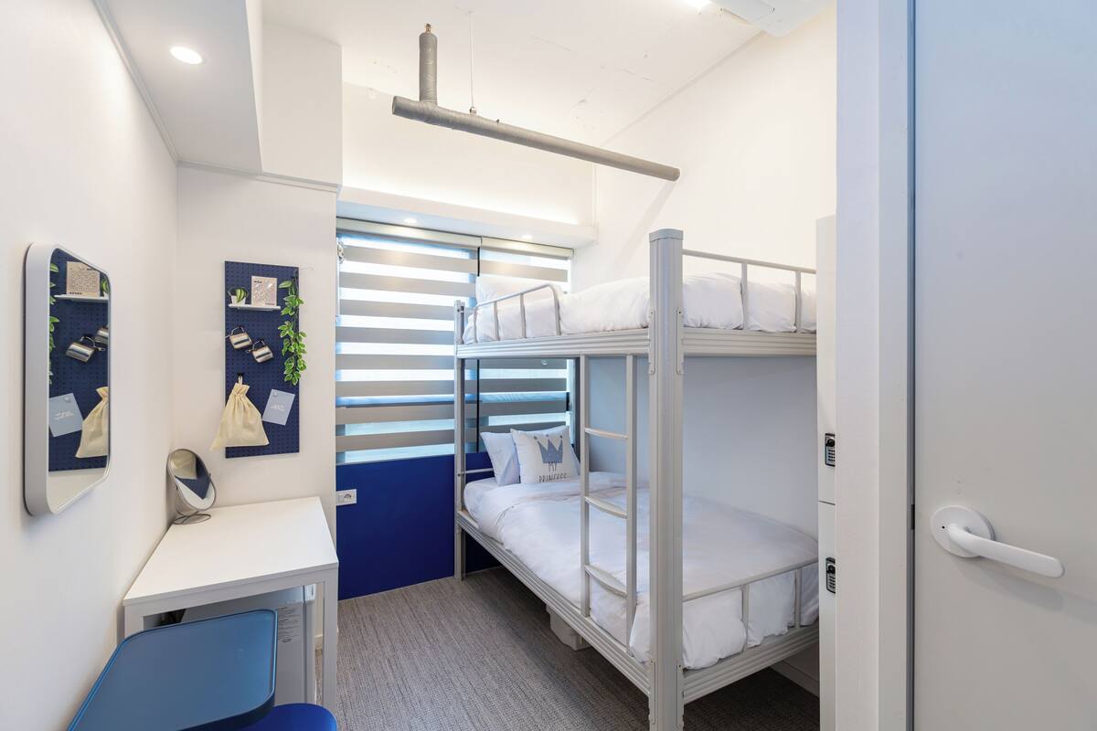 A bunk bed room with a desk and chair, a mirror, and a small plant.