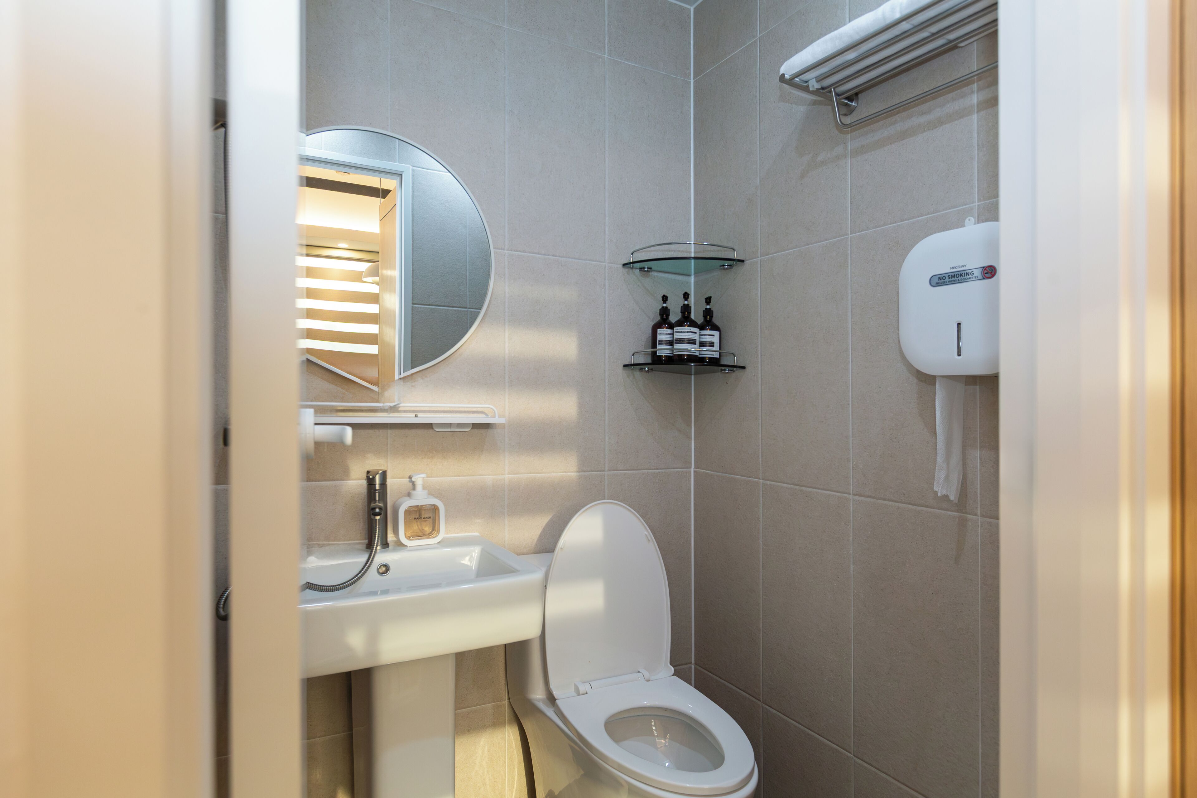 A modern bathroom with a toilet, sink, mirror, and hand dryer.