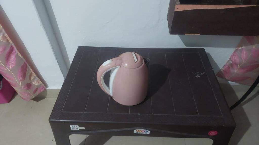 A pink kettle on a black table with a sticker that reads "AXPO".