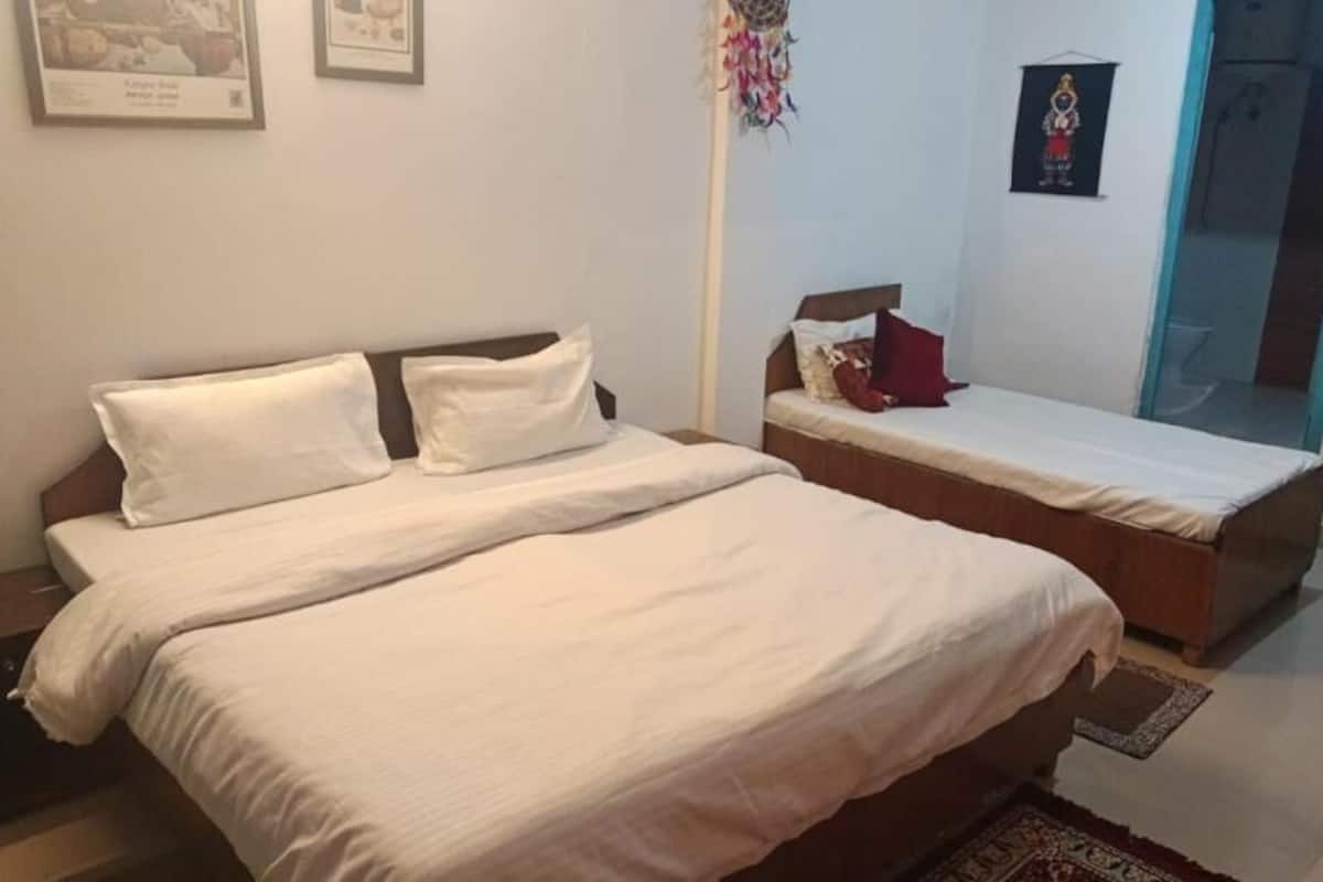 A bedroom with a large bed, a smaller bed, and a nightstand.