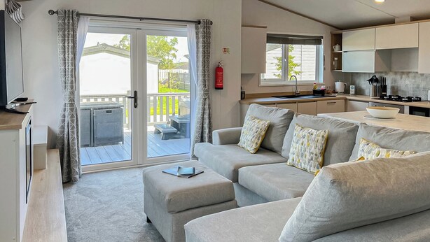Ein modernes Wohnzimmer mit Sofa, Hocker und einem Essbereich mit Tisch und Stühlen.