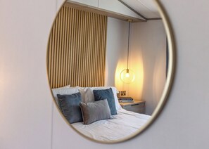 Une chambre à coucher avec un lit, des oreillers, une table de chevet, une lampe et un mur avec des lattes verticales.